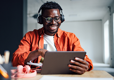 Male student wearing headphones working an a tablet 