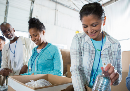 Image of two women and one man volunteering and packing a food box