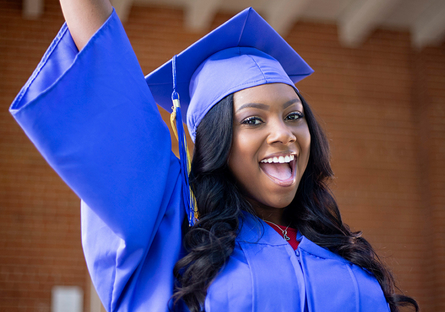 Image of a happy woman with her arm raised wearing a cap and gown