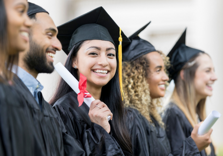 Image of a group of graduates with a woman smiling holing a diploma