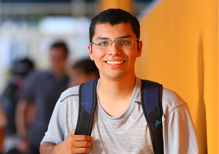 Image of a smiling male student wearing a gray T-shirt and navy backpack