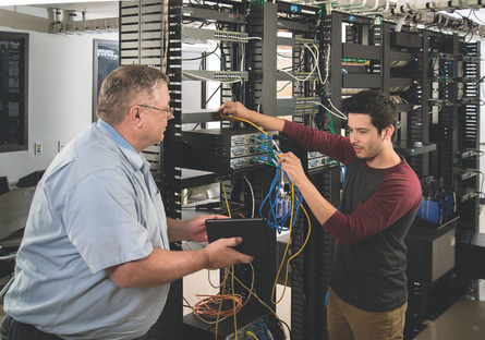 Image of a student and teacher working on IT servers