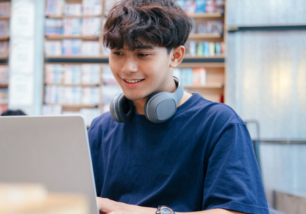 A student wearing a blue T-shirt using a laptop 