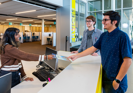 Image of a community college employee hand a brochure to a students