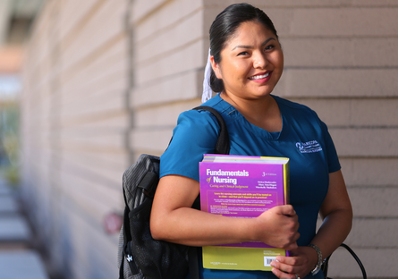 Image of a smiling nursing student wearing scrubs and holding books