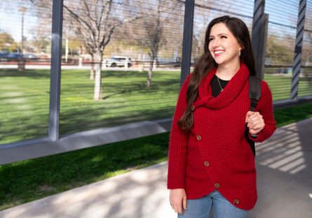 Image of a smiling woman walking outside wearing a red sweater