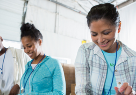 Image of two women and one man volunteering and packing a food box