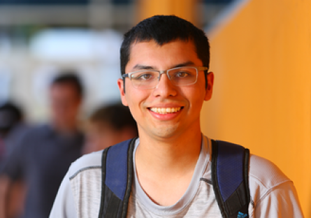 Image of a smiling male student wearing a gray T-shirt and navy backpack