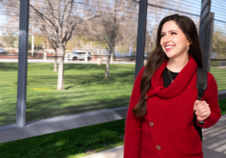 Image of a smiling woman walking outside wearing a red sweater